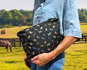 Woman on a horse pasture holding zipper pouch with equestrian pattern