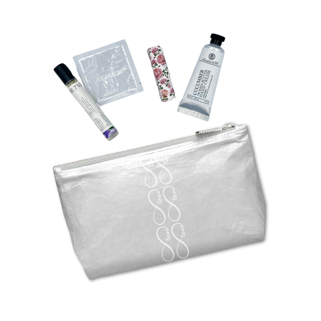 Silver cosmetic zipper pouch with toiletries laid out