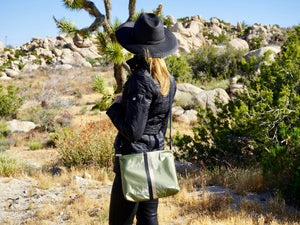 Woman standing in Joshua Tree wearing shimmer olive green crossbody purse