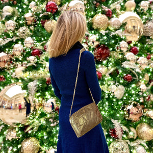 Woman in front of decorated Christmas tree wearing mini puffer purse with chain strap