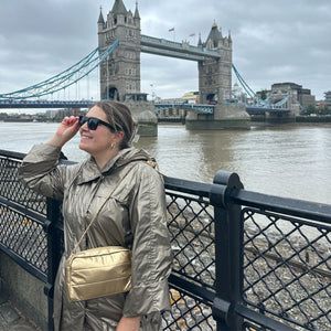 Woman standing in front of bridge in Ireland wearing gold mini puffer chain purse