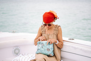 Woman in a boat looking inside sea green turtle patterned zipper pouch