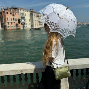 Woman standing near Italian waterfront wearing shimmer olive green mini puffer purse