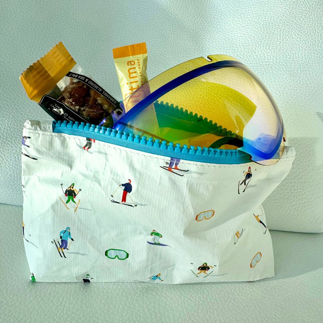 White mini zipper pouch with skiers and goggles pattern and ski goggles inside