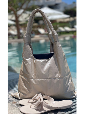 Shimmer beige puffer tote and beige sandals sitting on edge of pool