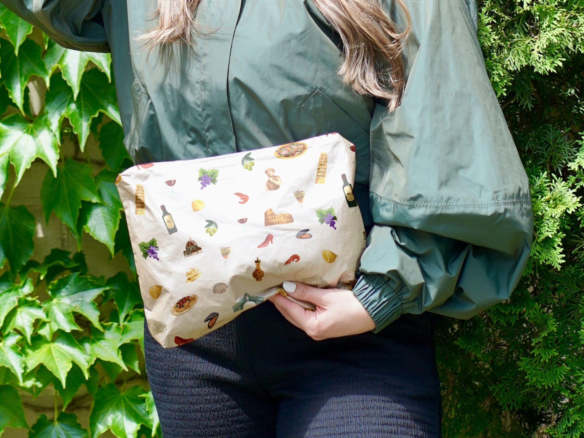 Woman in green blouse holding shimmer beige zipper pouch with Italy characters pattern