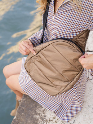 Woman in checkered dress wearing shimmer bronze crossbody backpack