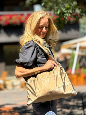 Woman standing in the sun with a shimmer bronze shoulder bag