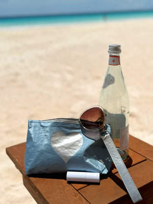 Shimmer ice blue with silver heart wristlet sitting on a beach table