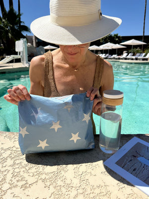 Woman standing at edge of pool with shimmer ice blue and silver stars zipper pouch