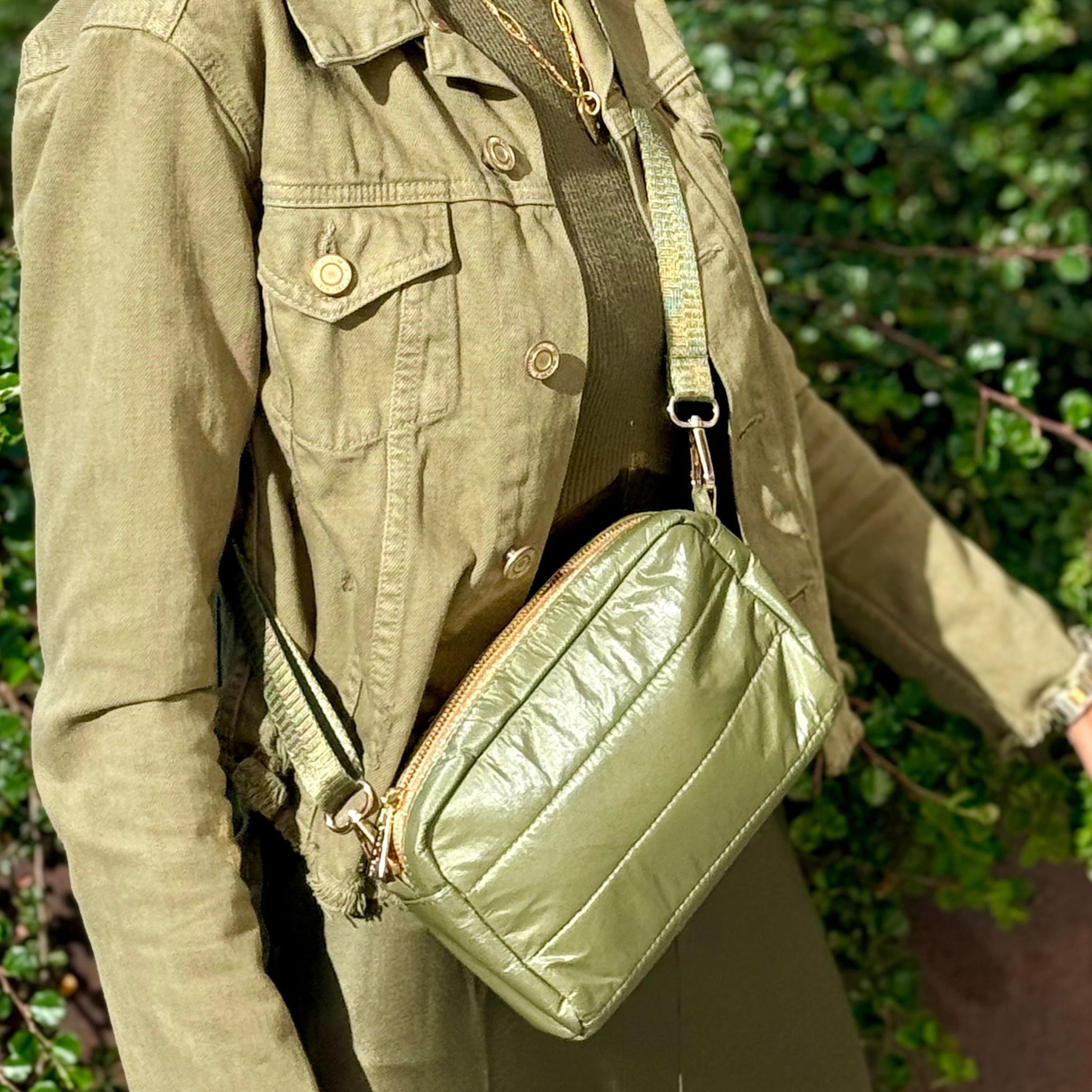 Woman wearing green dress, jacket, and shimmer olive green crossbody puffer purse