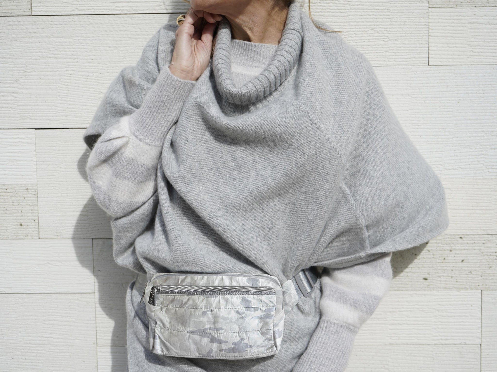 Woman in gray sweater wearing a shimmer white and gray camo fanny pack