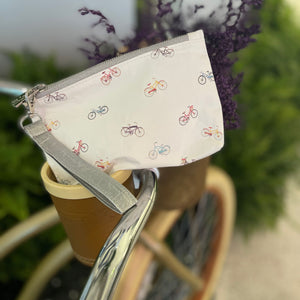 Mini white zipper pouch with myriad of colorful bicycles pattern sitting on top of a bike