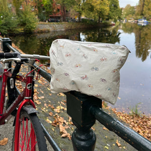 Medium white zipper pouch with colorful bicycles pattern sitting on next to a bicycle