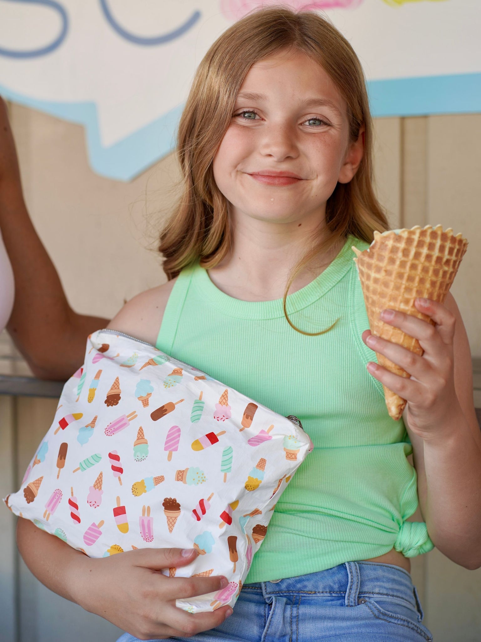 Smiling young girl holding an ice cream cone and an ice cream cone patterned zipper pouch